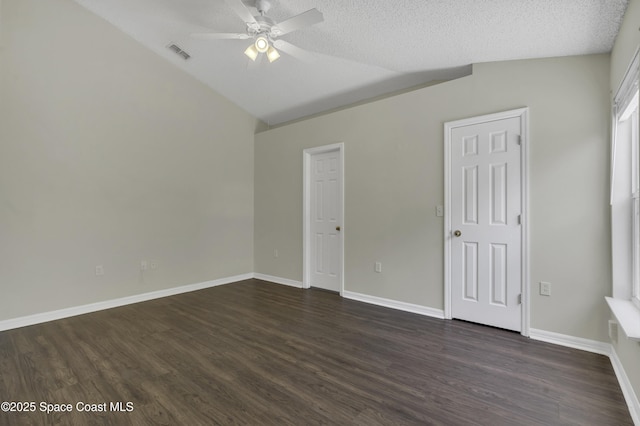 unfurnished bedroom featuring dark wood-style flooring, a textured ceiling, baseboards, lofted ceiling, and visible vents