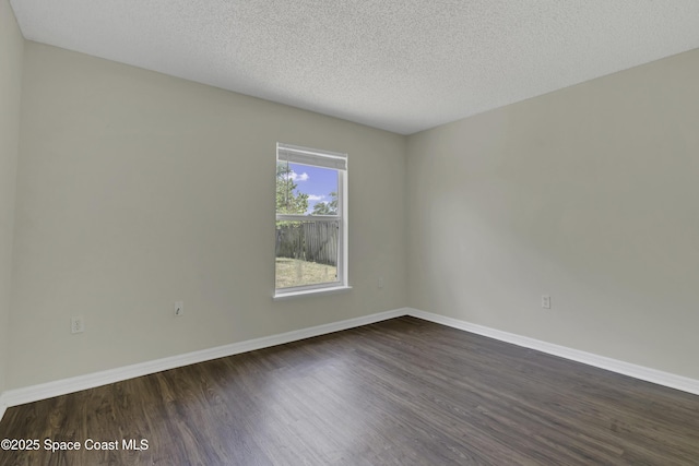 empty room featuring baseboards, dark wood-style floors, and a textured ceiling