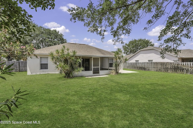 back of house featuring a fenced backyard, roof with shingles, stucco siding, a sunroom, and a yard