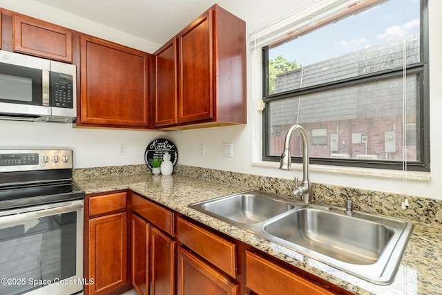 53 Piney Branch Way Unit D, West Melbourne, FL 32904 - kitchen with a sink, light stone counters, stainless steel appliances, and reddish brown cabinets
