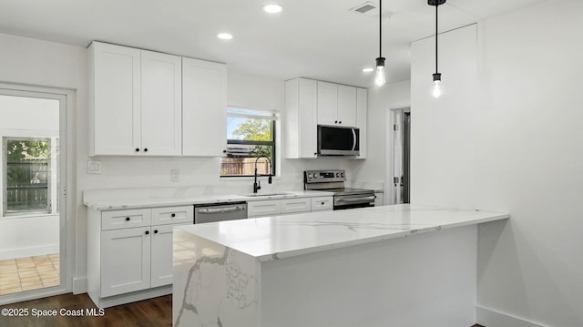kitchen with a sink, stainless steel appliances, recessed lighting, white cabinetry, and a peninsula