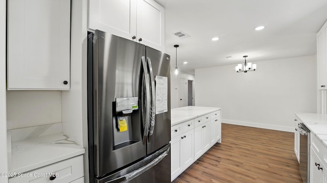 kitchen with wood finished floors, baseboards, white cabinets, a notable chandelier, and stainless steel appliances