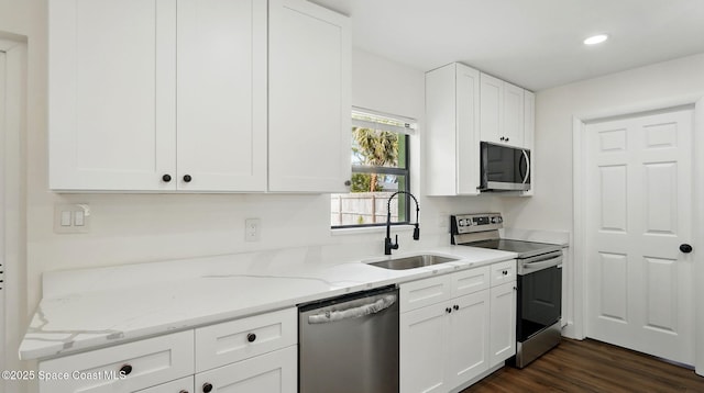 kitchen with white cabinetry, light stone countertops, appliances with stainless steel finishes, and a sink
