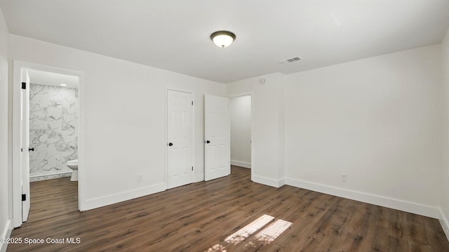 unfurnished bedroom with baseboards, wood finished floors, and visible vents