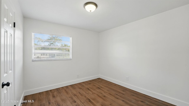 spare room with baseboards and wood finished floors