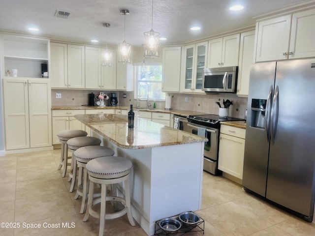 kitchen featuring a kitchen island, visible vents, open shelves, light stone counters, and stainless steel appliances