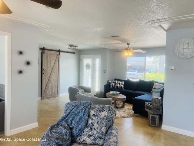 living room with a barn door, a textured ceiling, ceiling fan, and light tile patterned floors