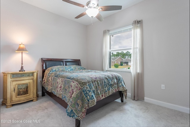 bedroom featuring baseboards, light colored carpet, and ceiling fan