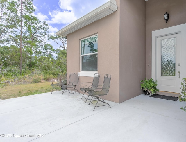 entrance to property with a patio and stucco siding