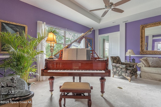 living area with carpet floors, a ceiling fan, a raised ceiling, and visible vents