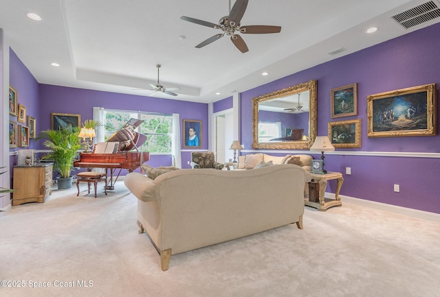 carpeted living area featuring a raised ceiling, ceiling fan, recessed lighting, and visible vents