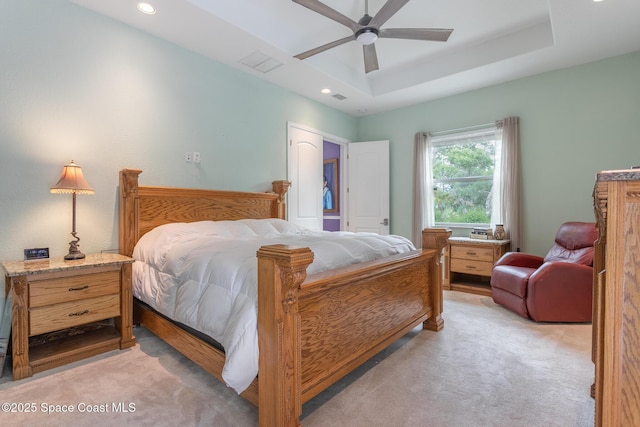 bedroom featuring light carpet, a tray ceiling, and recessed lighting