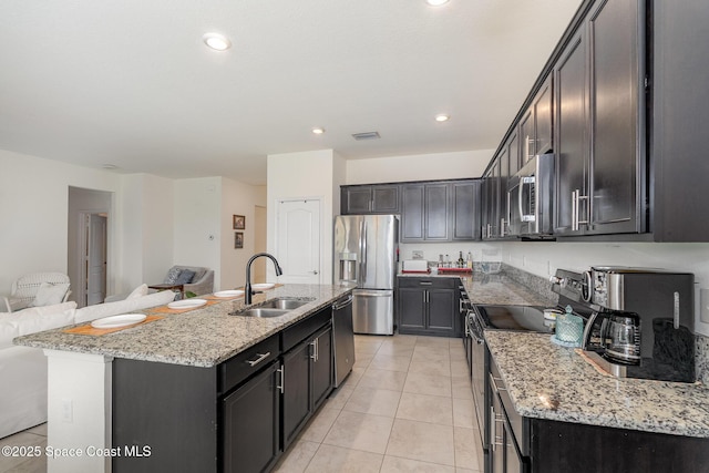 10033 W Verona Cir, Vero Beach, FL 32966 - kitchen featuring light stone counters, a sink, stainless steel appliances, open floor plan, and light tile patterned floors