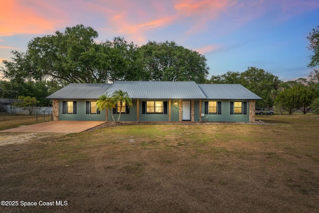ranch-style house featuring fence, stucco siding, a lawn, driveway, and metal roof