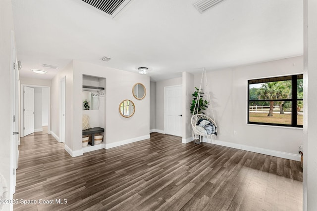interior space with baseboards, wood finished floors, and visible vents