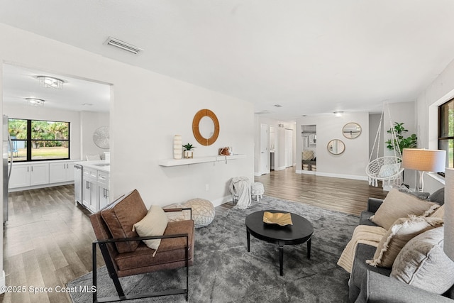 living area with visible vents, baseboards, plenty of natural light, and wood finished floors