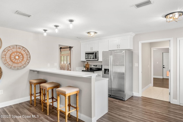 kitchen with dark wood-style floors, stainless steel appliances, visible vents, and a breakfast bar