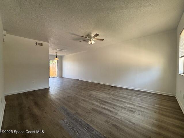 spare room featuring visible vents, baseboards, dark wood-style floors, a textured ceiling, and a ceiling fan