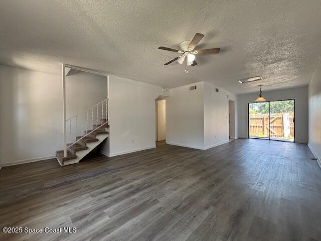 unfurnished living room with baseboards, ceiling fan, dark wood-style floors, and a textured ceiling
