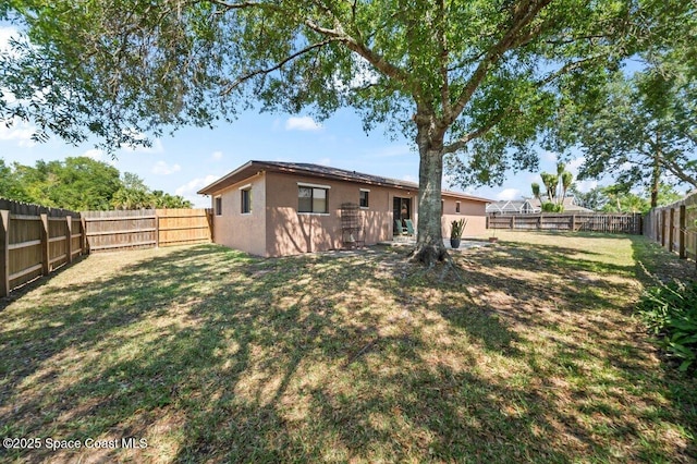 back of property with a lawn, stucco siding, and a fenced backyard