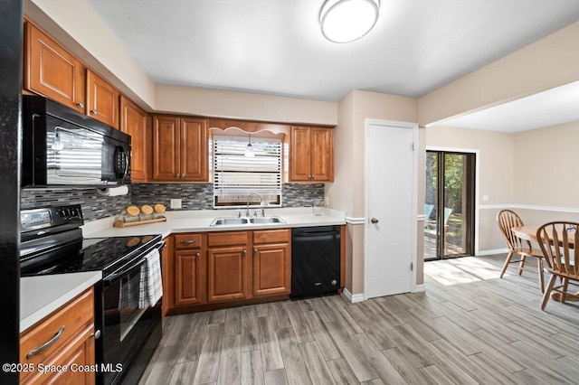 kitchen featuring a sink, tasteful backsplash, black appliances, and brown cabinets