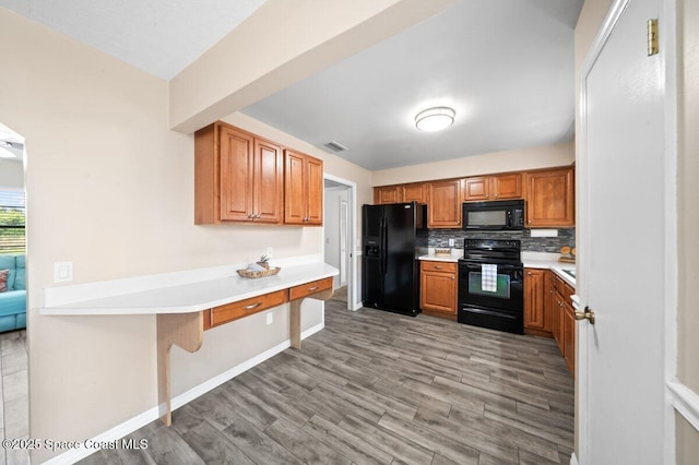 kitchen with light wood-style floors, light countertops, brown cabinetry, decorative backsplash, and black appliances