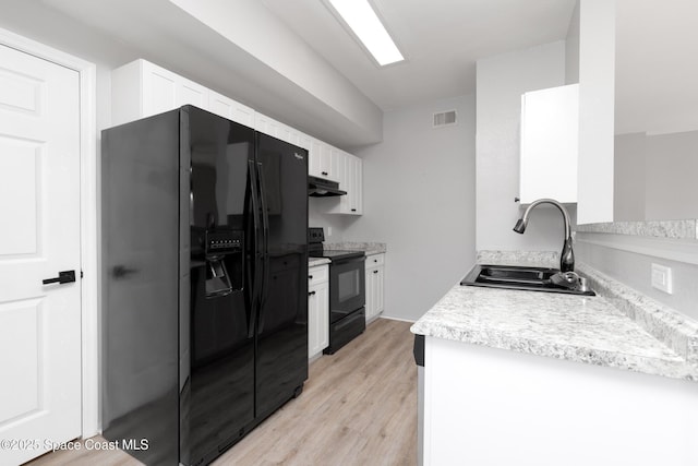 kitchen featuring white cabinets, a sink, under cabinet range hood, visible vents, and black appliances