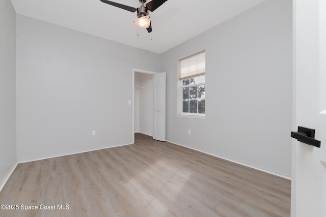 empty room with ceiling fan, baseboards, and light wood-style floors