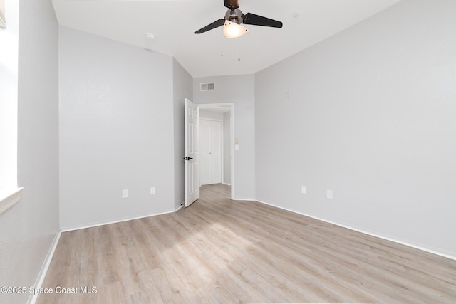spare room featuring visible vents, a ceiling fan, light wood-style floors, and baseboards