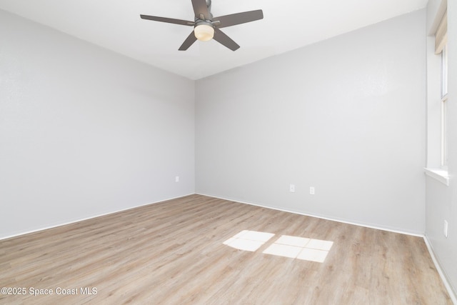 empty room featuring light wood-style floors, a ceiling fan, and baseboards