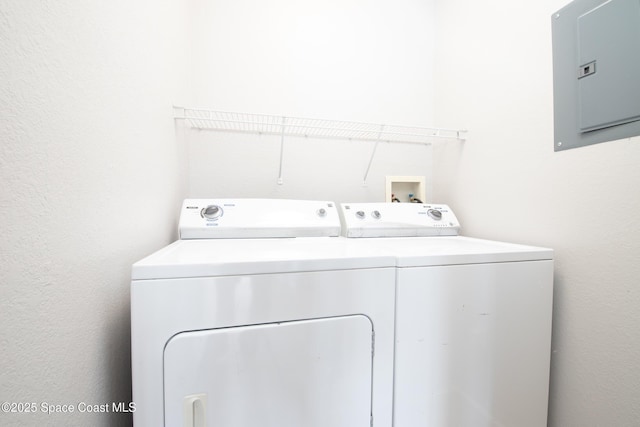 laundry room featuring a textured wall, laundry area, washing machine and dryer, and electric panel