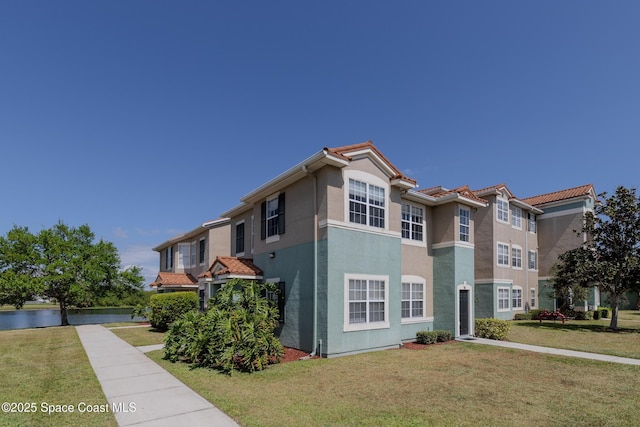 exterior space featuring stucco siding, a yard, and a tiled roof