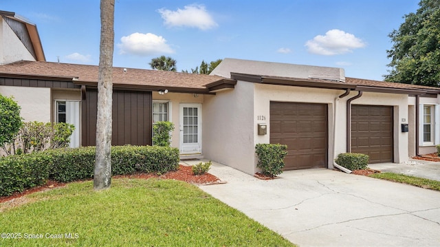 single story home featuring a garage, stucco siding, driveway, and a front lawn