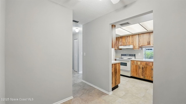 kitchen with light countertops, visible vents, under cabinet range hood, and electric stove