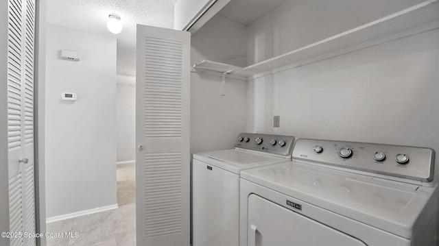 laundry room with baseboards, laundry area, washing machine and dryer, and a textured ceiling