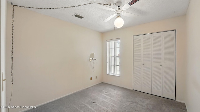 unfurnished bedroom with a ceiling fan, visible vents, carpet floors, baseboards, and a closet