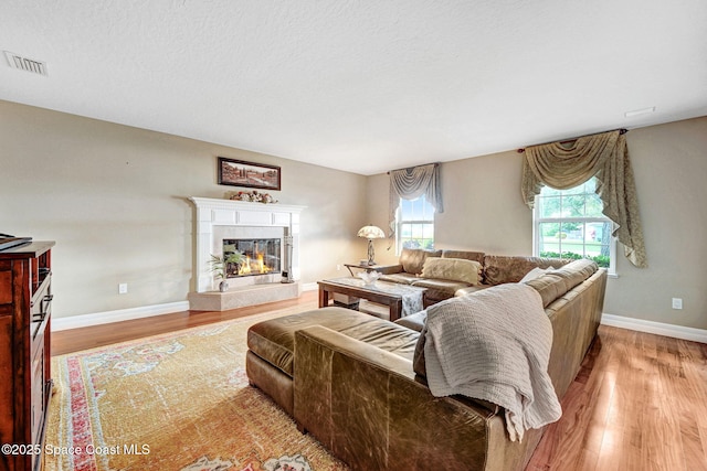 1428 Gleneagles Way, Rockledge, FL 32955 - living area with light wood-style flooring, a glass covered fireplace, baseboards, and visible vents