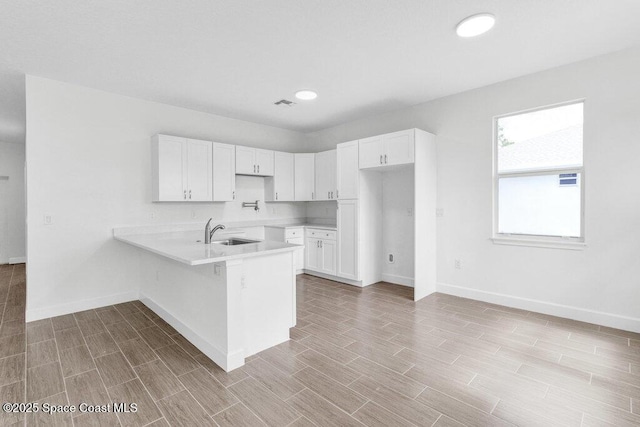 8050 96th Ave, Vero Beach, FL 32967 - kitchen with a sink, a peninsula, light countertops, baseboards, and white cabinets