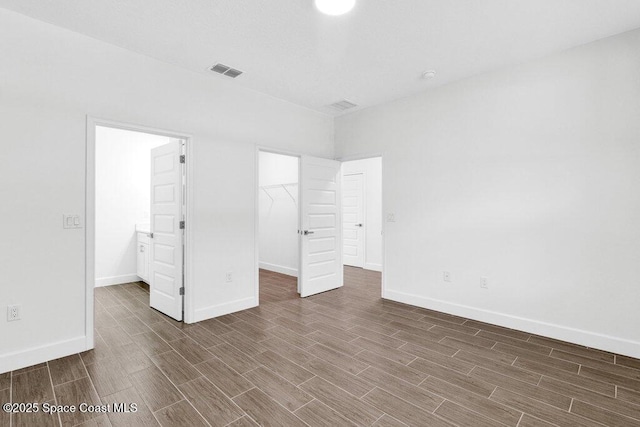8050 96th Ave, Vero Beach, FL 32967 - unfurnished bedroom with wood finished floors, a spacious closet, baseboards, and a closet