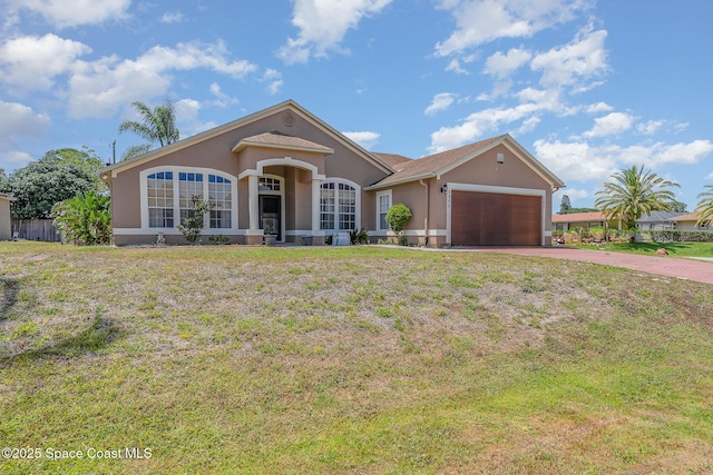 single story home featuring a garage, a front lawn, stucco siding, and driveway