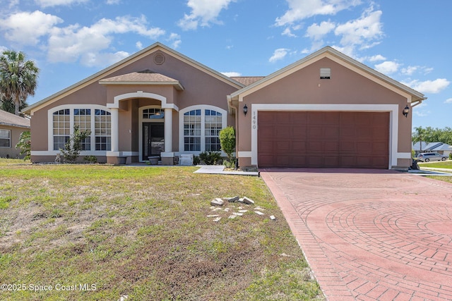 view of front of property featuring a garage, stucco siding, decorative driveway, and a front yard