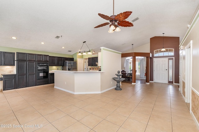 kitchen with light tile patterned flooring, stainless steel fridge, light countertops, dobule oven black, and vaulted ceiling