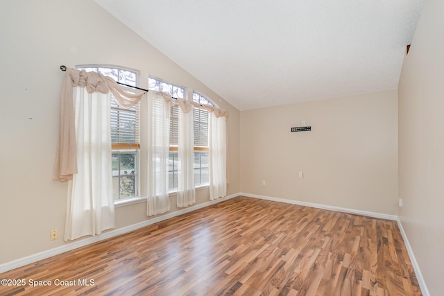 spare room with vaulted ceiling, wood finished floors, and a wealth of natural light