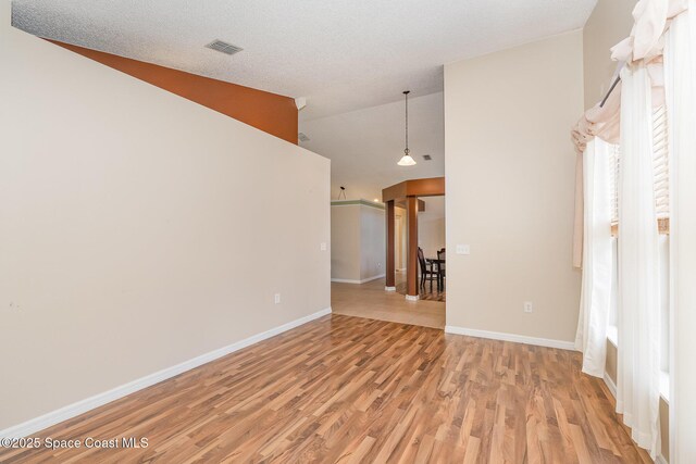 empty room with baseboards, visible vents, high vaulted ceiling, and light wood-type flooring