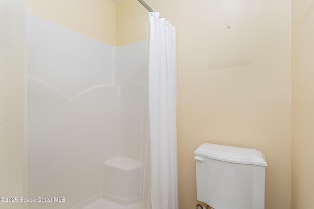 full bath with toilet and a shower with shower curtain