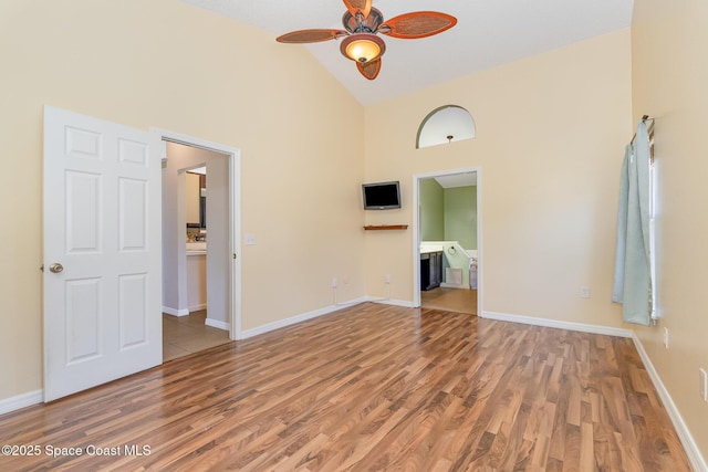 spare room featuring high vaulted ceiling, baseboards, a ceiling fan, and wood finished floors
