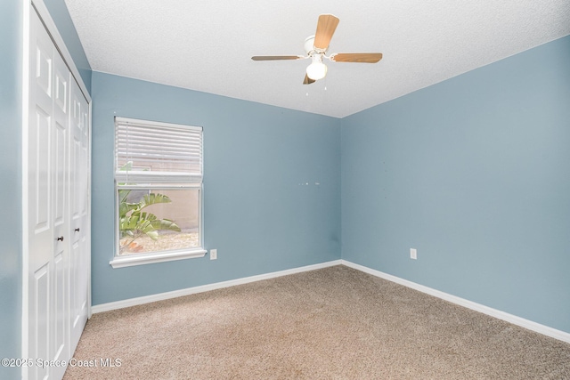 unfurnished bedroom featuring carpet floors, baseboards, a closet, and ceiling fan