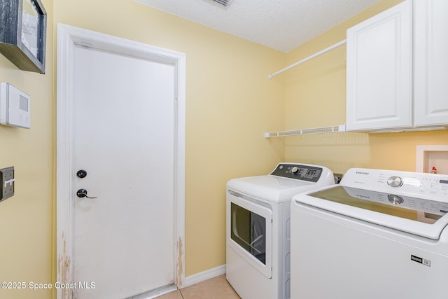laundry room featuring cabinet space, light tile patterned flooring, separate washer and dryer, a textured ceiling, and baseboards
