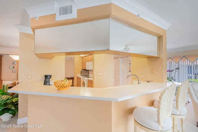 kitchen with visible vents, crown molding, a peninsula, white appliances, and a ceiling fan