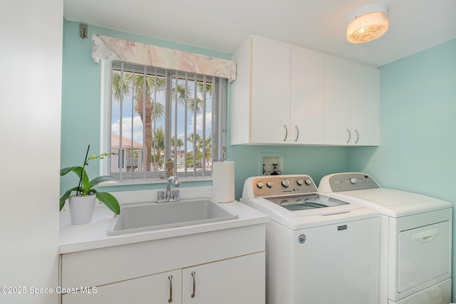 clothes washing area with a sink, washer and clothes dryer, and cabinet space
